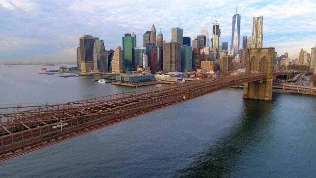 Aerial Backward Shot Of Brooklyn Bridge On River In Modern City Under Clouds In Sky - New York, New York