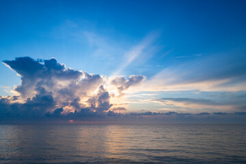 Sunset on tropical beach sea ocean with sunrise clouds. Banner for travel vacation. Scenery sky and reflection rays in water. Dusk, twilight on sea. Tranquil, golden sky background.