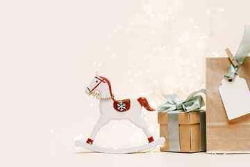 Gift box with green bow. christmas rocking horse and lights garland background, copy space. Boxing...