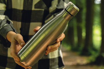 Close-up of Unrecognizable female hand holding Water bottle. Reusable steel thermo water bottle in...