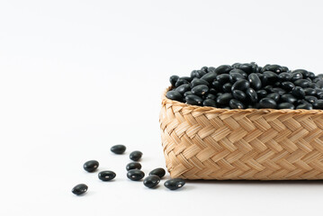 Black beans are placed in a wicker container and put on a white background, space for text.