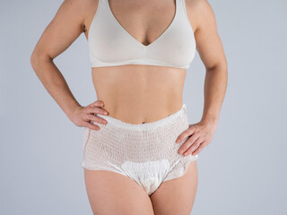 Woman in adult diapers on a white background. Incontinence problem.