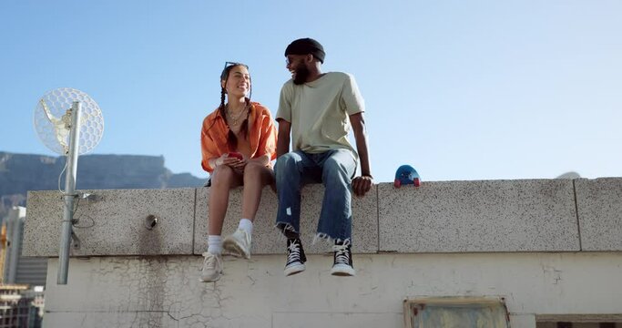Love, friendship and a couple sitting on rooftop of city building in summer time. Diversity, friends and romance, gen z urban dating for happy woman and black man with smile and skateboard on date.