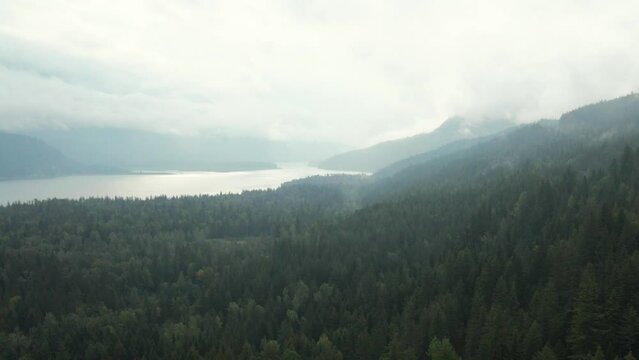Slow aerial dolly through fog showing Upper Arrow Lake, Canada