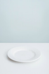 An empty white plate on a light kitchen table. Photo minimalism
