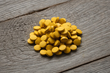 Yellow Turmeric pills on the wooden background,  Curcuma longa soperfood and dietary supplement