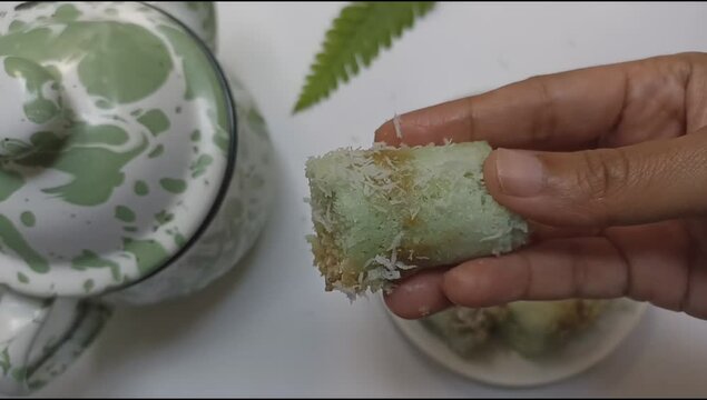 Hand open kue putu bamboo or putu cake. Viewing the deliciousness of brown sugar inside the rice flour which sprinkled with grated coconut.