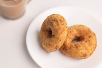 plate of methu vadai with cup of tea on table.