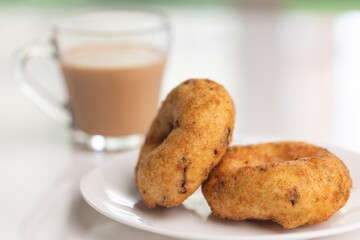 plate of methu vadai with cup of tea on table.