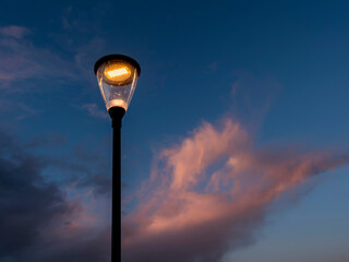 Modern powerful LED light in old style lantern against blue cloudy sunset sky. City and town illumination tool. Energy saving light.