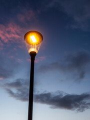 Modern powerful LED light in old style lantern against blue cloudy sunset sky. City and town illumination tool. Energy saving light.