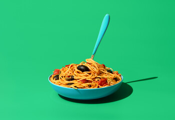 Pasta puttanesca dish, minimalist on a green background