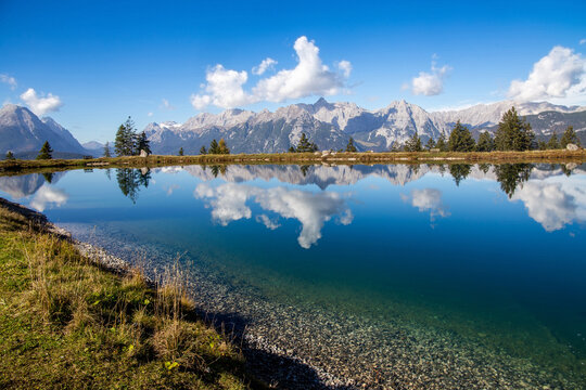 Der Kaltwassersee in Seefeld/Tirol. Die Berge und die Wolken spiegeln sich im kalten klaren Wasser des Bergsees