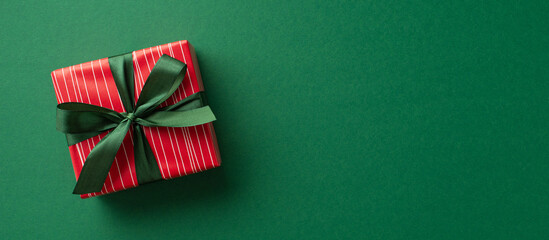 New Year concept. Top view photo of trendy red giftbox with ribbon bow on isolated green background with copyspace
