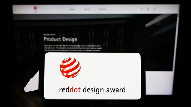 Stuttgart, Germany - 10-15-2022: Person holding smartphone with logo of German international prize Red Dot Design Award on screen in front of website. Focus on phone display.