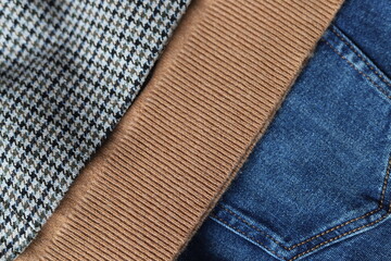 Woolen checked blazer, cashmere sweater, blue jeans. Close up.