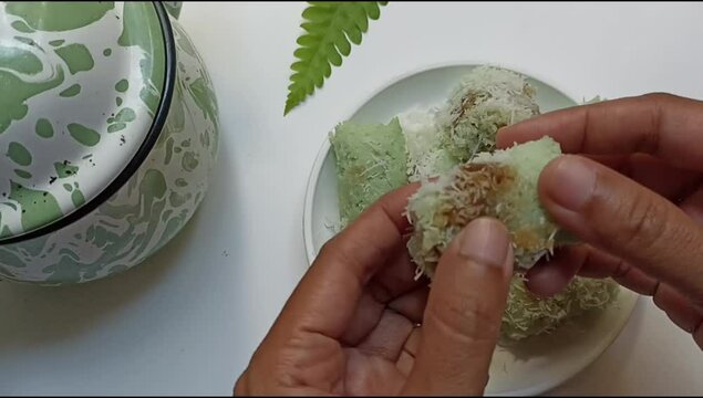 Hand open kue putu bamboo or putu cake. Viewing the deliciousness of brown sugar inside the rice flour which sprinkled with grated coconut.