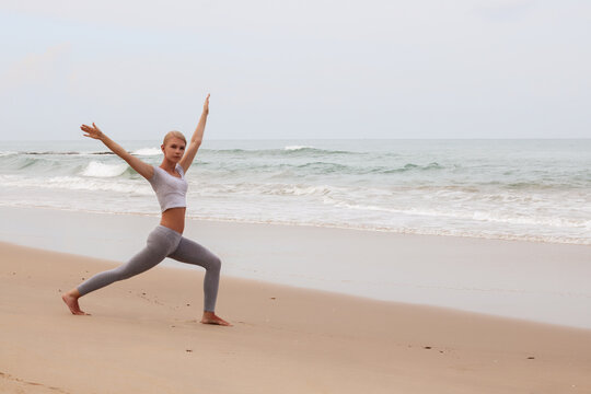 Beautiful attractive young woman exercising yoga on the empty beach,Summer woman vacations concept.