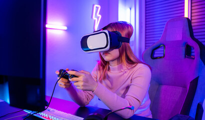Gamer in VR headset glasses exploring metaverse play video game online with joystick on computer neon lights, Excited woman virtual playing gamepad controller she very determined at home © sorapop