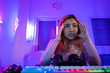 Game Over. Asian gamer playing online video game she losing and sad on computer PC colorful neon...