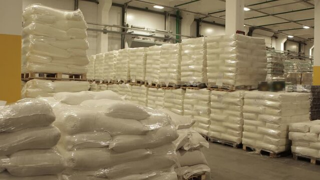 Sacks of sugar and flour on pallets lie in the warehouse. Import and export of goods. Business and logistics, industry.