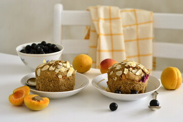 Fototapeta na wymiar Muffins with apricots and black currants sprinkled with almond flakes