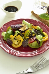 Colorful tomatoes salad with eggplant, cucumber, corn and basil, vertical