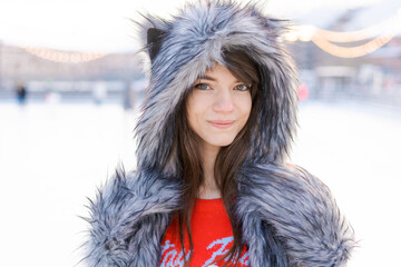 Portrait cute young woman in shaggy hat with ears looks at camera and smiles against the background...