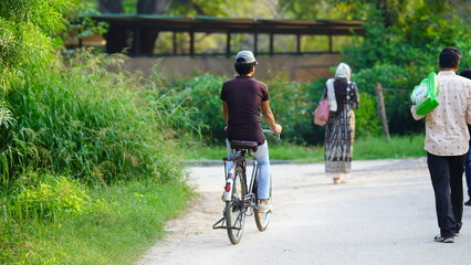 a poor man wearing a hat riding a bicycle on the road