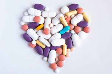 Pharmacy background on a white table. Close up of different kind of pills and capsules in heart shape.
