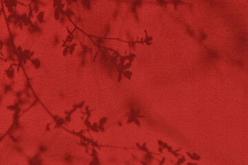Shadow of leaves and flowers on red concrete wall texture with roughness and irregularities....