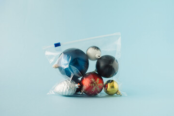 Various Christmas decorations packed in a plastic zip bag on blue background. Minimal holiday greeting concept. © Maja