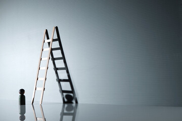 wood figurine and step ladder lean on the gray background