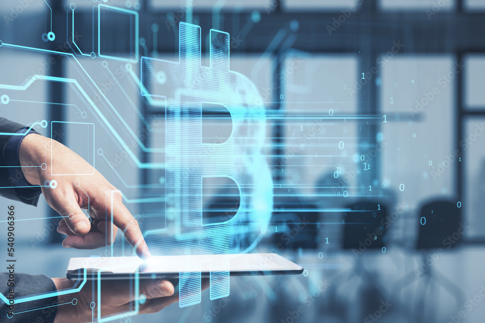 Poster close up of businessman hand pointing at tablet with glowing bitcoin hologram on blurry office inter