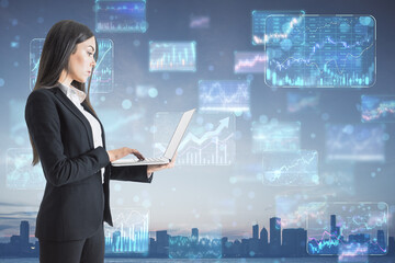 Investing, trading and forex exchange concept with view on businesswoman using laptop on digital wall background with financial chart diagrams, arrows and graphs on screens on city skyline background
