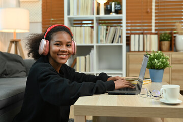 Smiling young African woman watching learning online in virtual classroom on laptop. E-learning education concept