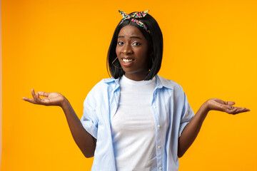 African young woman standing over yellow background with clueless and confused expression and hands...