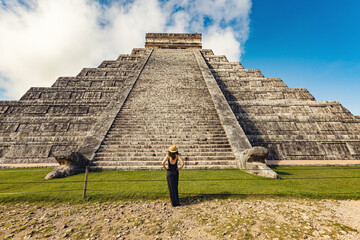 Woman wearing hat and black dress (back view, unrecognized) in front of the Chichen-Itza pyramid in...