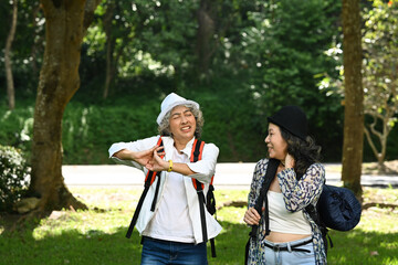 Obraz premium Joyful senior women talking each other while walking at nature park. Retirement, people and outdoor activity concept
