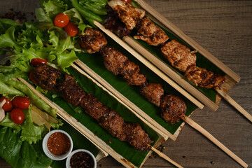 Grilled meat skewers served in bamboo barrel plate with Chinese spices and vegetable on rustic...