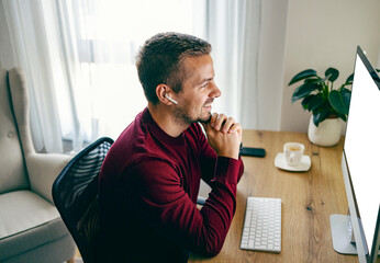 A freelancer is having online business meeting with his employer and working from home while...