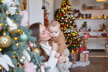 Mother with baby on background of Christmas tree. Christmas family.