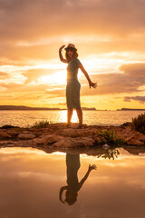 Sunset in Ibiza on vacation, a young woman waving in San Antonio Abad. Balearic
