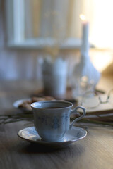 Cup of tea, plate with chocolate chip cookies, open book, reading glasses, lit candles and dry lavender flowers. Hygge at home, selective focus.