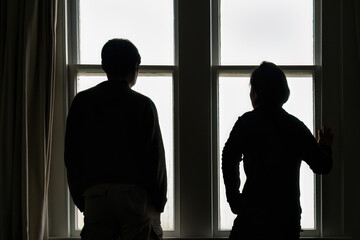 Couple standing by the window with condensation, looking outside.