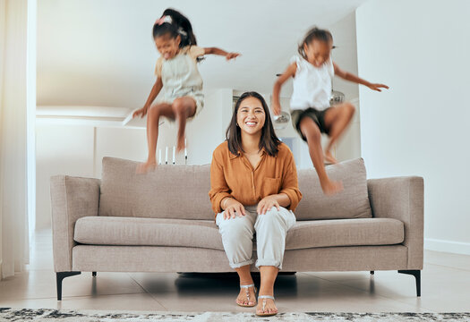 Family, mom and kids jumping on sofa having fun, energetic and hyper at home. Happiness, joy and portrait of mother sitting with excited children jump on couch, play and relax together on weekend