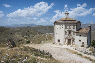 Fototapeta na wymiar The church of Santa Maria della Pietà in Rocca Calascio with the beautiful Abruzzo mountains and hills in the background