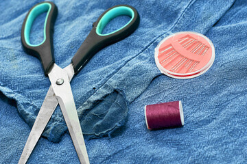 scissors needles and thread on the background of torn jeans concept reasonable consumption of small business needlework
