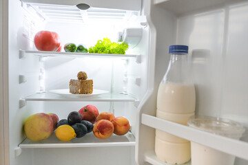 Refrigerator with sweets and fruits and vegetables.Piece of cake and healthy food.Diet...