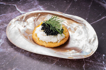 Black caviar served on an elegant shell with scrambled eggs and lemon on crackers.